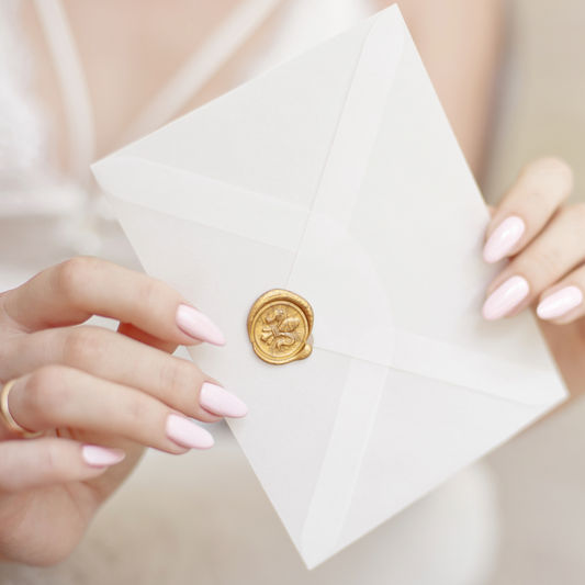 A bride holding a white envelope with a gold seal on it