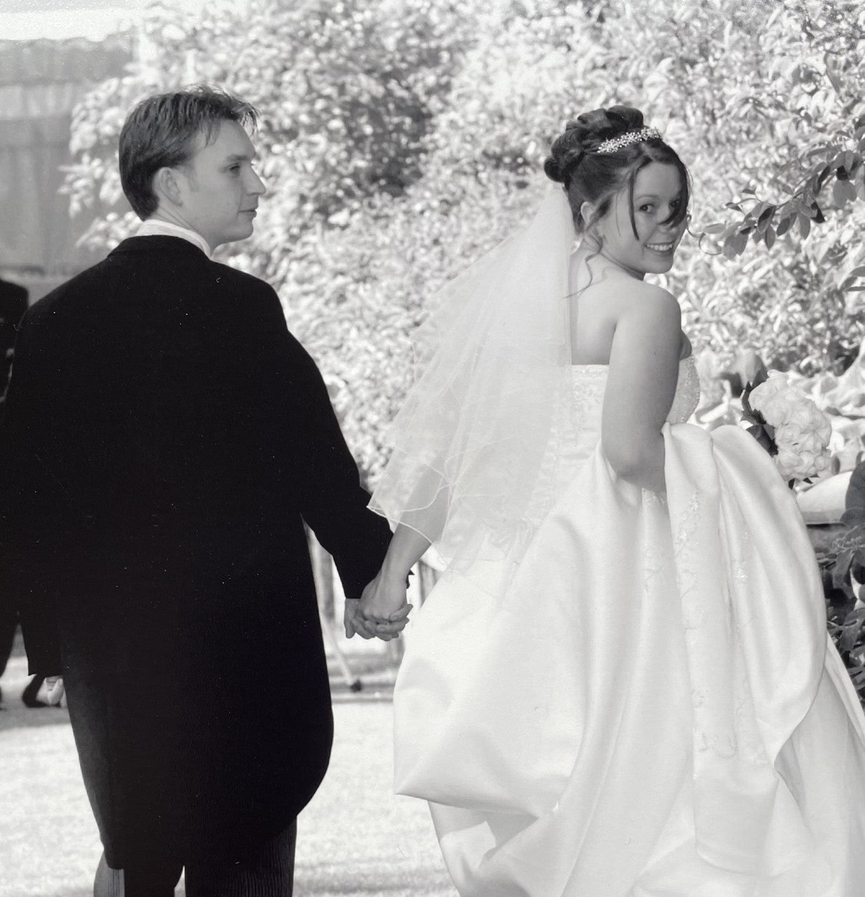 The founder of Mr & Missive in her wedding dress smiles back at the camera while walking with her new husband.