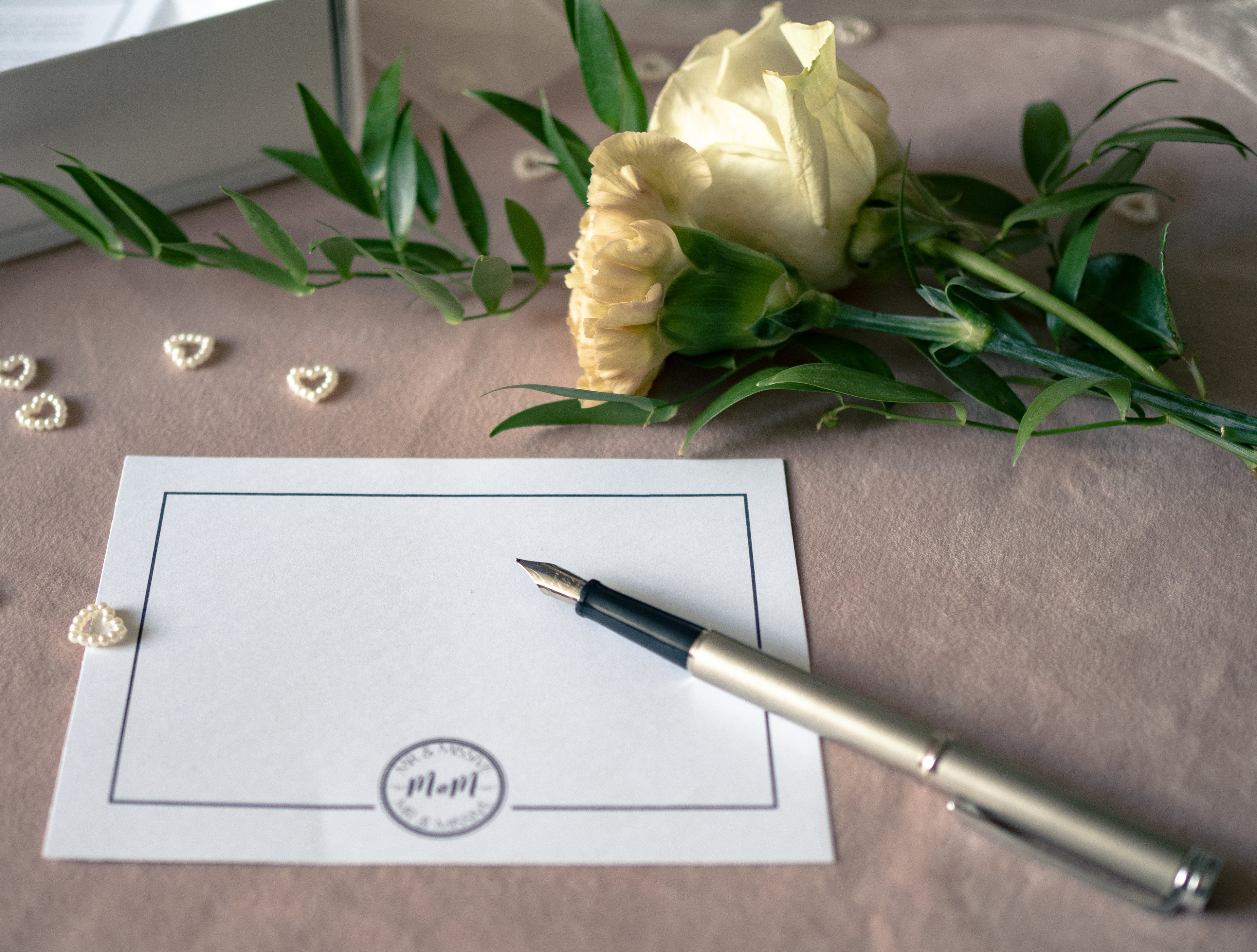 Photograph of a Mr & Missive luxury postcard with a fountain pen, shown with flowers in the background.