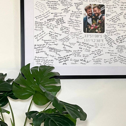 A handwritten Mr & Missive wedding guest book alternative from the Portrait Collection featuring a photograph centrepiece and a plant in the foreground.