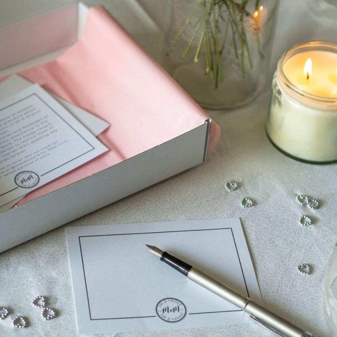 A Mr & Missive wedding guest book alternative postcard with fountain pen and a lit candle in the background.