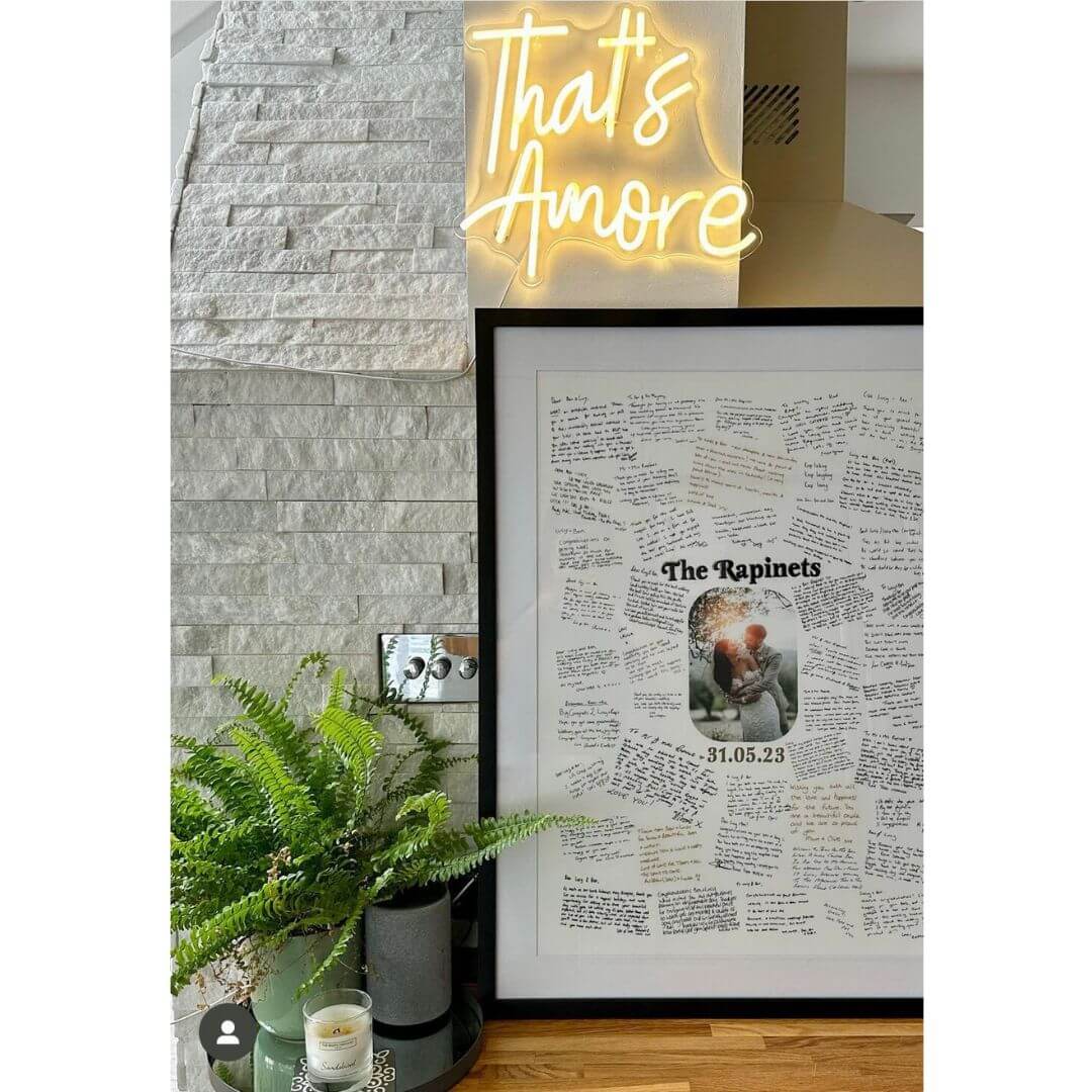 A handwritten Mr & Missive wedding guest book alternative from the Portrait Collection, featuring a photograph of a bride and groom with their name and wedding date either side, positioned against a wall with a plant in the foreground.